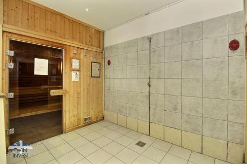 a bathroom with a shower and a tiled wall at ARC 1950 Appartement 2 chambres cabine 8 personnes in Arc 1950
