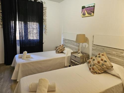 a room with two beds and a lamp and a window at Apartamento Caballito de Mar con PARKING in L'Estartit