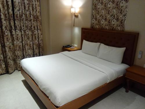 a bedroom with a large bed with white sheets at The Hub Link in Mumbai