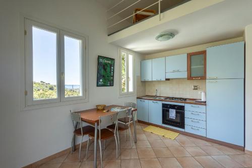 a kitchen with white cabinets and a table and chairs at U Ciousu by Ligurian Life APPARTAMENTI IN AGRITURISMO in Vallebona