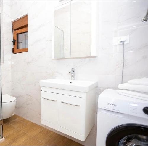 a white bathroom with a sink and a washing machine at Apartmani Milos - Meljine in Herceg-Novi