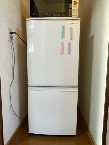 a white refrigerator with a microwave on top of it at Minpaku SAKURA 民泊 戸建貸切 彦根城まで車10分 無料駐車場 普通2台小型1台 in Hikone