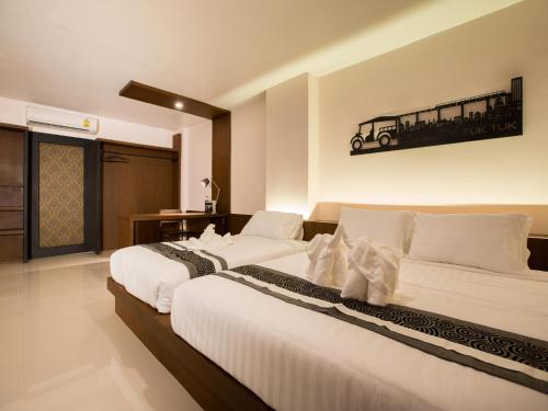 two beds in a hotel room with a train picture on the wall at iChapter Hotel Suvarnabhumi in Samutprakarn