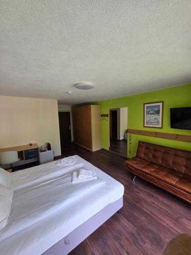 a hotel room with two beds and a couch at Grischalodge das Hotel mit Bergblick seit 1929 - schlicht, preiswert und mit einem touch Nostalgie in Parpan