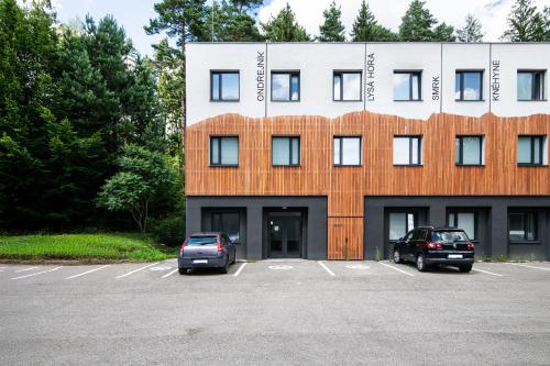 a building with two cars parked in a parking lot at Beskydy House in Rožnov pod Radhoštěm