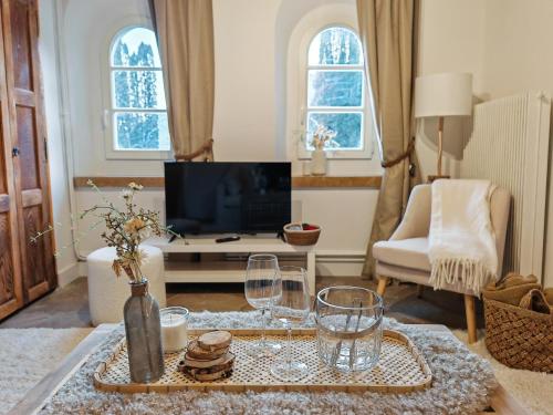 a living room with a television and a table with wine glasses at Beauregard Jura - Countryside Estate Stays Near Geneva in Gex