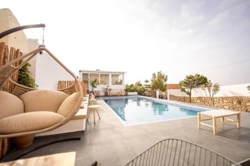 a swimming pool with a chair and a couch next to a building at Villa Sahel Bleu in Essaouira