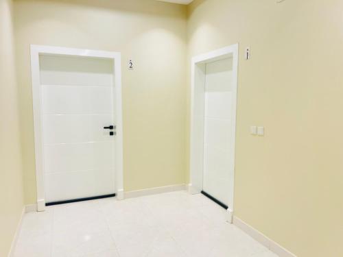 two doors in a room with white walls at Village Sunset ڤيلـج سانـست in Al Namas