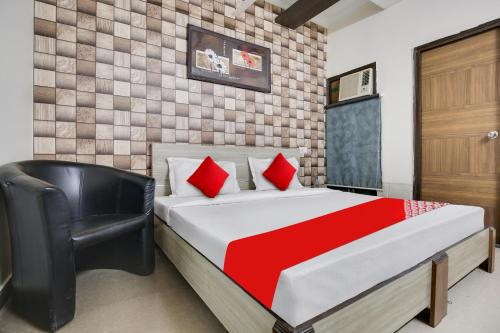 a bedroom with a bed and a black chair at Hotel O Inder Inn in Jalandhar