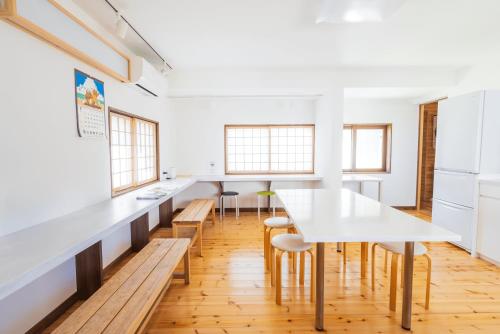 a kitchen with white counters and a table and chairs at つるのこ縁屋 in Nanyo