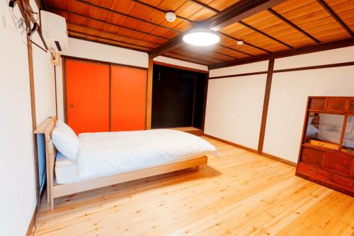 a bedroom with a bed and a wooden floor at つるのこ縁屋 in Nanyo