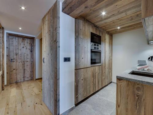 Il comprend une cuisine dotée de murs en bois et d'un réfrigérateur. dans l'établissement Appartement de Standing à Tignes, Proche Pistes et Commerces, 4 Chambres - FR-1-641-18, à Tignes