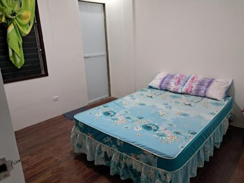 a small bed in a room with a blue sheet at House for rent Rizal, Laguna San Pablo City in Rizal