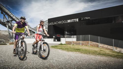 two people riding bikes in front of a building at Appartements Kuprian in Längenfeld
