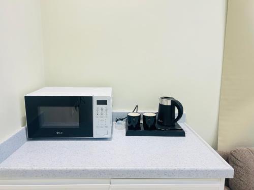 a microwave oven sitting on a counter with two mugs at Village Sunset ڤيلـج سانـست in Al Namas