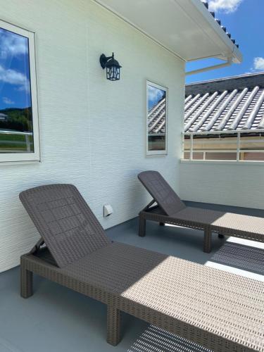a patio with two chairs and a table and a window at アオイカゼ in Awaji