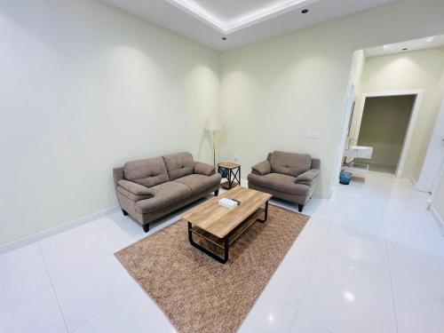 a living room with two couches and a coffee table at Village Sunset ڤيلـج سانـست in Al Namas