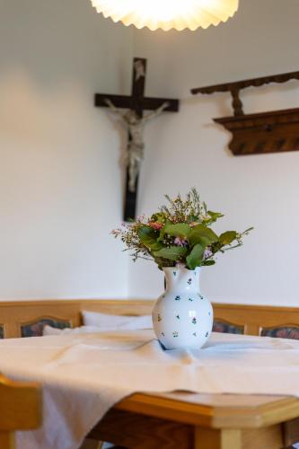 a vase with flowers on a table with a cross at Gasthof Waldschenke in Bad Leonfelden