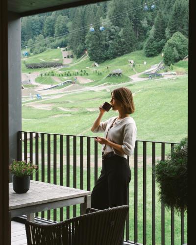 a woman standing on a balcony talking on a cell phone at Boutique Hotel Das Rivus in Leogang