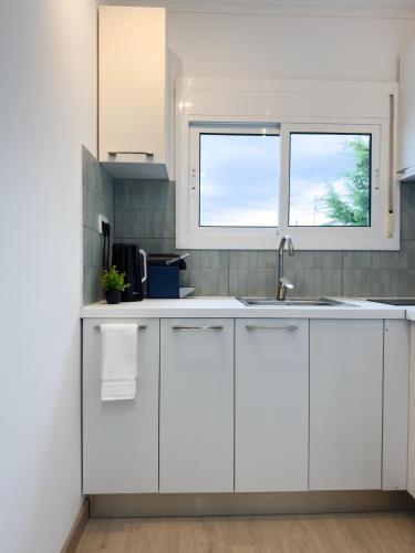 カンブリルスにある111 - Beachside Renovated 1BR apt 5 min from Beachの白いキャビネットと窓のあるキッチン
