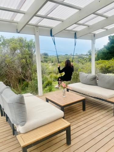 a woman sitting on a porch swinging on a swing at Coastal Nature Escape on Kangaroo Island in Pelican Lagoon