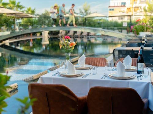 a table with plates and a vase of flowers on top of a pool at Gloria Palace Hotel & SPA in Golem