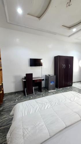 a bedroom with a large white bed and a desk at The Marble Hotel and Apartments in Uyo