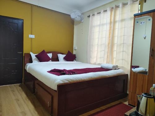 a bedroom with a large bed with purple pillows at KDM Guest House in Cherrapunji
