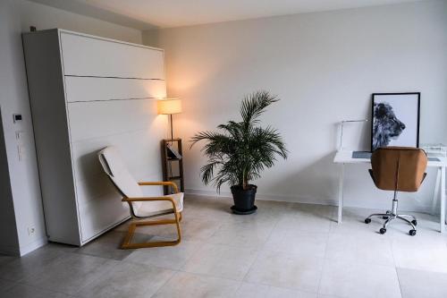 a living room with a chair and a plant at Neue moderne Wohnung,74qm,Balkon,Kingsize Boxspringbett in Offenburg