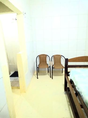 a room with two beds and two chairs at Residencial Praia Bertioga Pé na Areia in Bertioga
