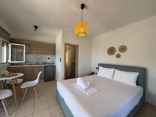 a bedroom with a large white bed and a kitchen at BLOOM Studios in Achillion Magnisia