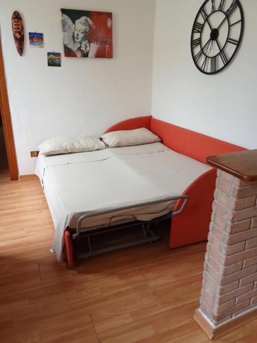 a bed in a room with a clock on the wall at Holiday House Ginevra in Formia