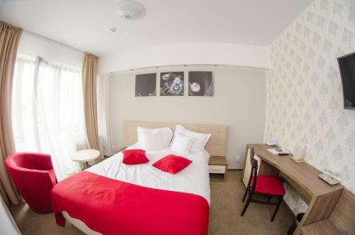 Habitación de hotel con cama roja y escritorio. en Potaissa Hotel, en Turda