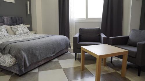 a bedroom with a bed and two chairs and a table at riad casa bahia asilah in Asilah