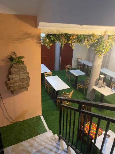 a restaurant with tables and chairs and a balcony at Da Palm Inn Abrui in Aburi