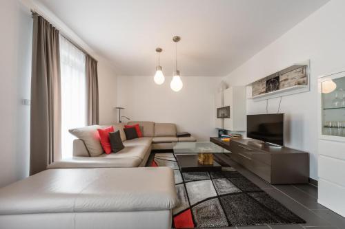 a white living room with a couch and a tv at Residence Salzgeber in Schruns-Tschagguns