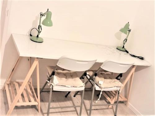 einen weißen Tisch mit zwei Stühlen und einer Lampe in der Unterkunft l'Etoile du Nord in Romainville