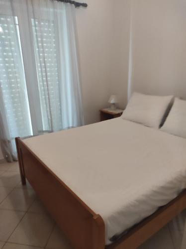 a bed in a bedroom with white walls and windows at Tasos Art in Káto Almirí