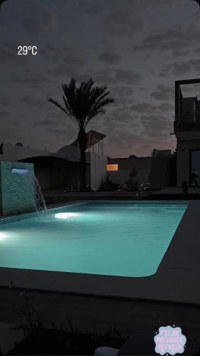 a swimming pool with blue lights in the night at Villa DEJRBA De LUXE in Houmt Souk