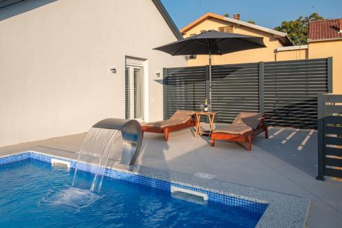 a pool with an umbrella and two chairs and a table at Luxury Grey house in Stolac