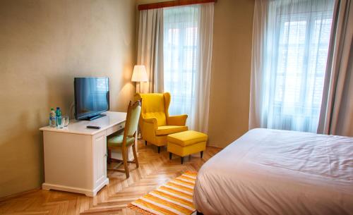 a hotel room with a bed and a desk with a television at Goldsmith in Sibiu