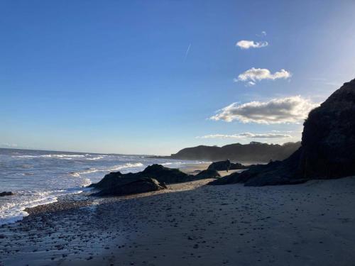 a sandy beach with rocks and the ocean at Peaceful Garden Studio near Gorey Sleeps 4 Parking in Gorey