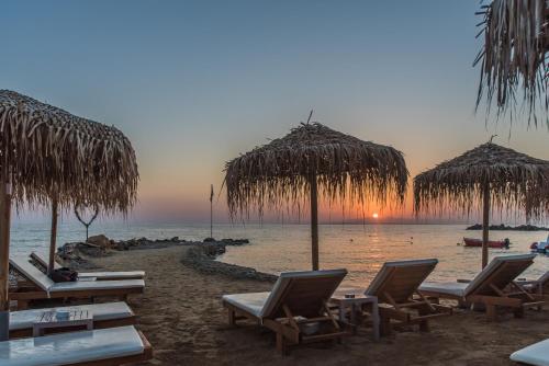 a group of chairs and straw umbrellas on a beach at Golden Coast Suites in Kipseli