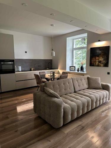 a living room with a large couch and a kitchen at Luxury Downtown Apartment in Klaipėda