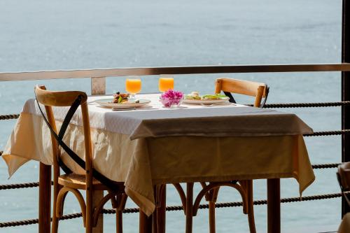 a table with two plates of food and two glasses of orange juice at Rea Boutique Hotel in Himare