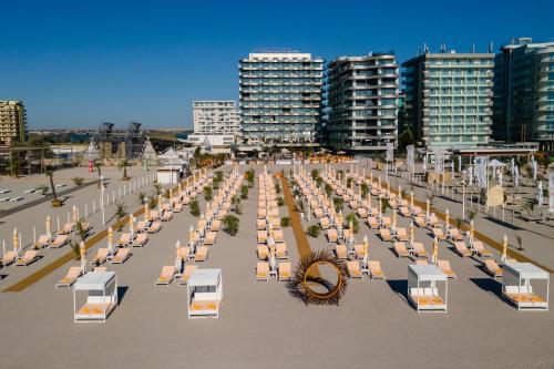 a row of tables and chairs on a beach with buildings at Crowne Plaza Constanta - Mamaia Beach by IHG in Mamaia