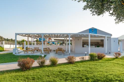 a pavilion with picnic tables and benches in a park at Olive Garden Hotel in Lardos