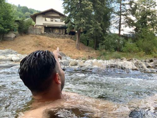 a man in the water in front of a house at Waterfall Guest House in Ribarica