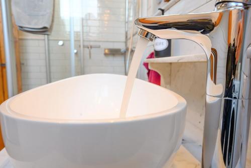 a white toilet with water pouring from a faucet at Ferienhaus Ottenhöfen - Sauna | Hot Tub in Ottenhöfen