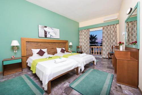 a bedroom with two beds and a balcony at Potamaki Beach Hotel in Benitses